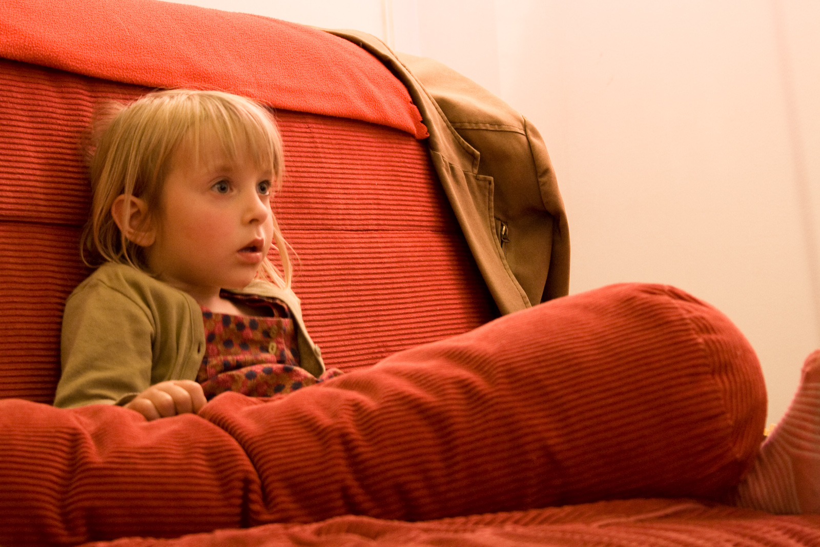 a little girl sitting on a red couch
