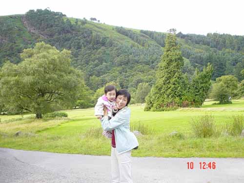 a woman is hugging her child while standing in front of the woods