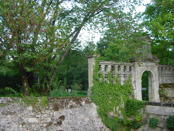 a stone wall and stone gate that have ivy growing on them
