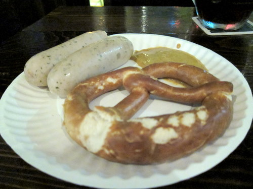 a paper plate topped with sausages next to a cup of wine