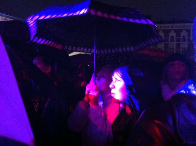 a woman holding an umbrella while a group of people are standing next to her