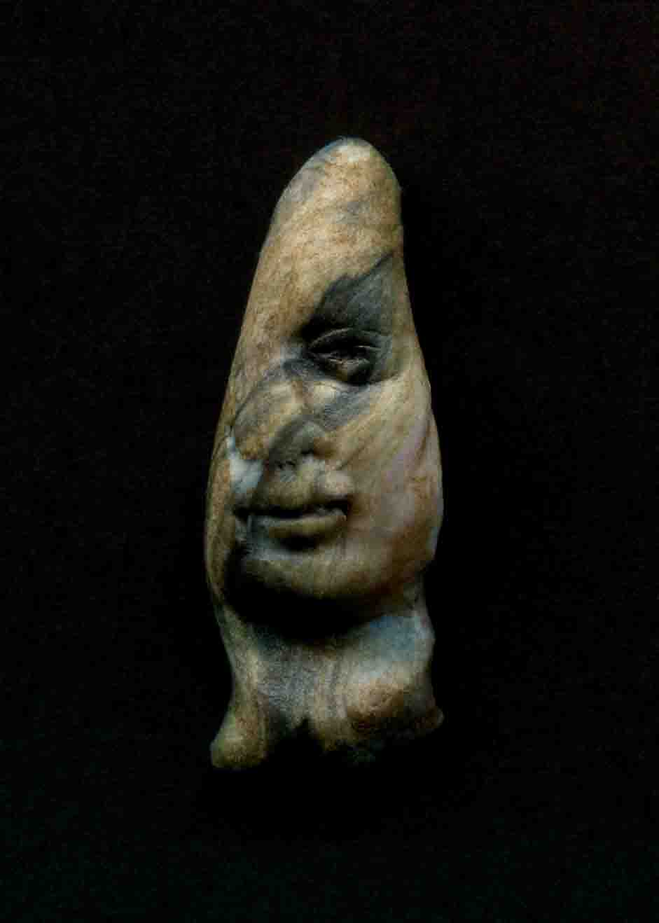 a clay face on a black surface with a dark background