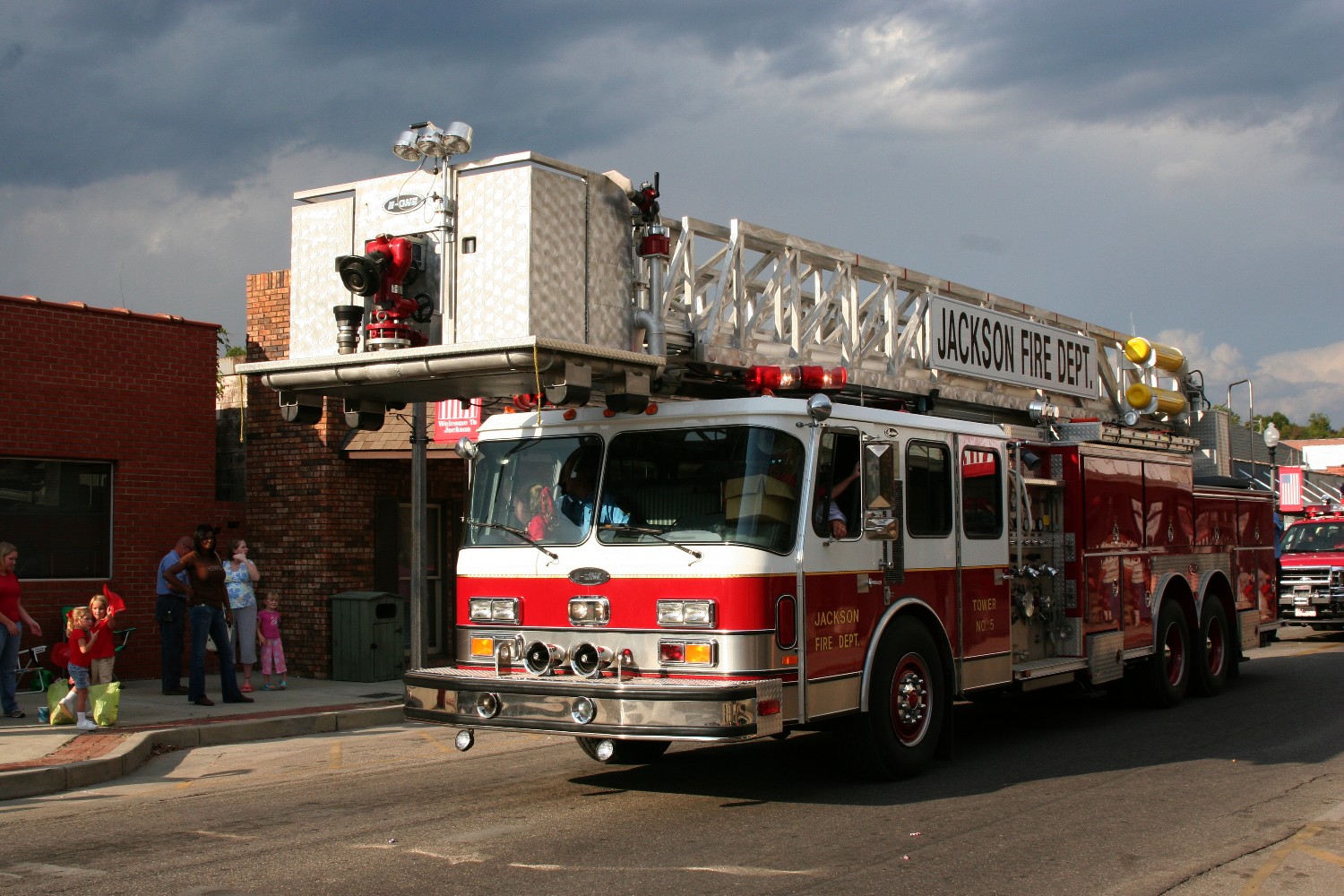 two fire engines sit on the street while people watch