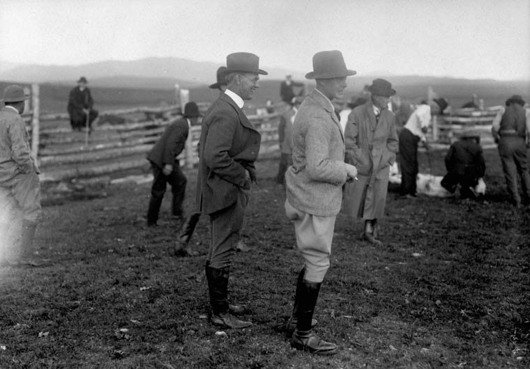 a couple of men are standing near a fence