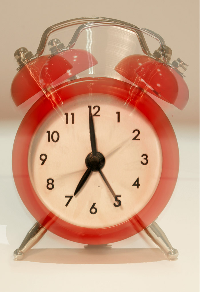 a shiny red alarm clock on white surface