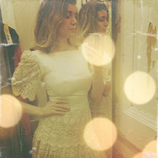 a woman stands in front of a mirror wearing a white dress