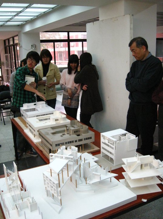 a group of people looking at models of buildings