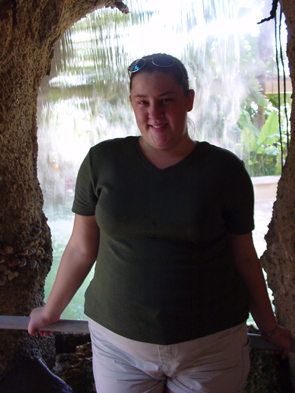 a woman standing behind an opening in a cave