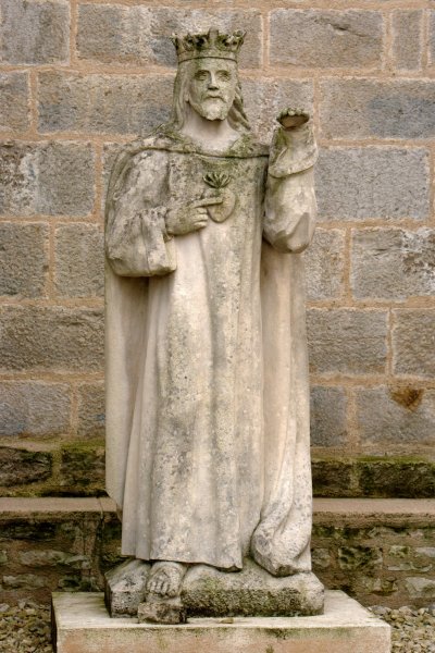 a statue of saint benedict stands in front of a brick wall