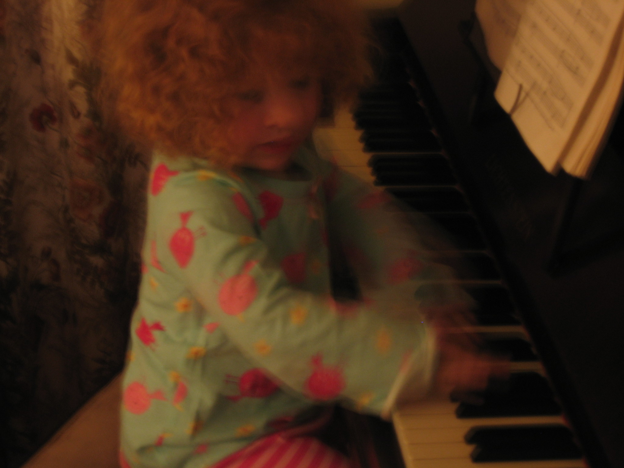 a little girl sitting at a piano playing the keyboard