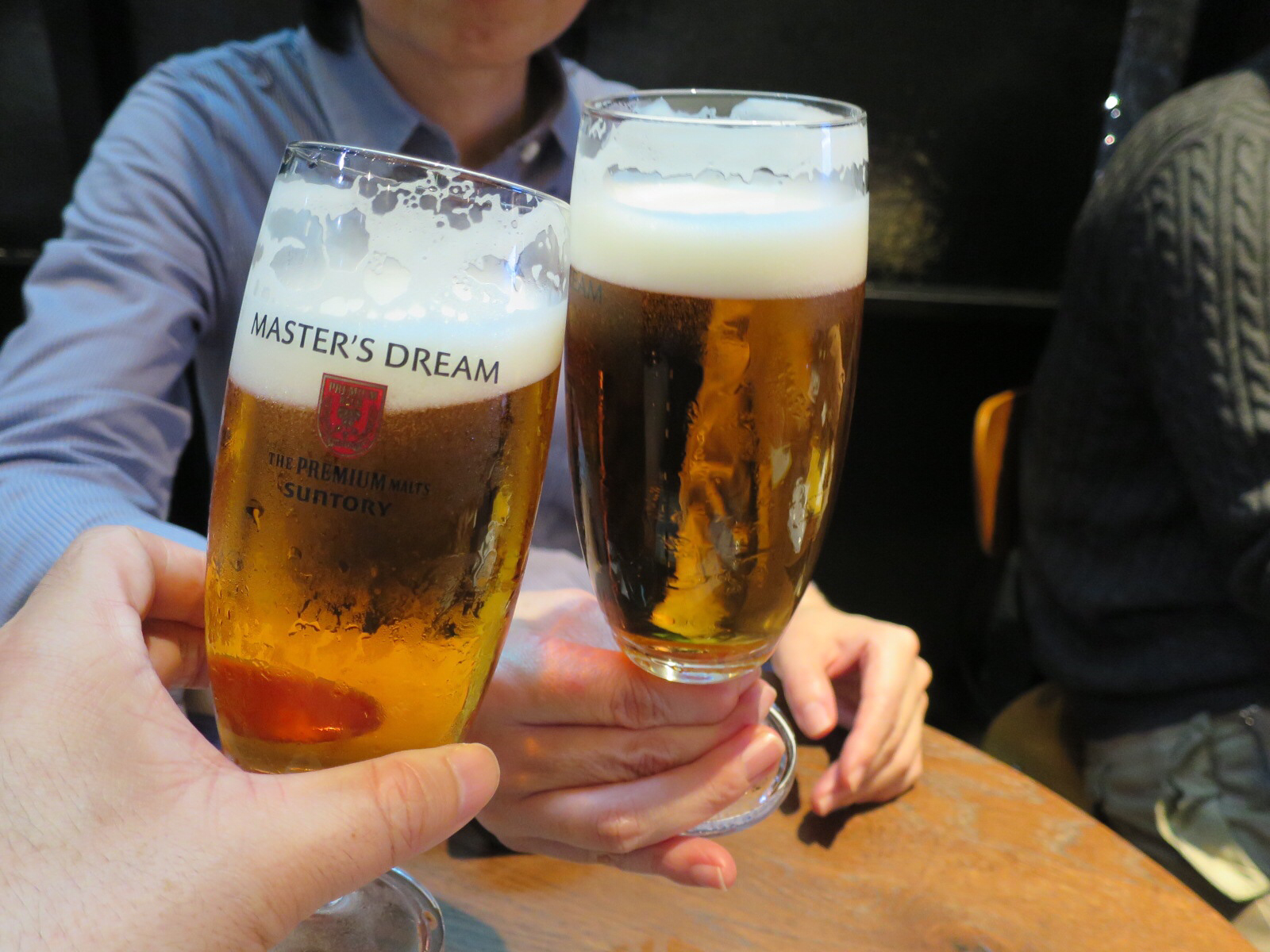 two people toasting and holding beer glasses