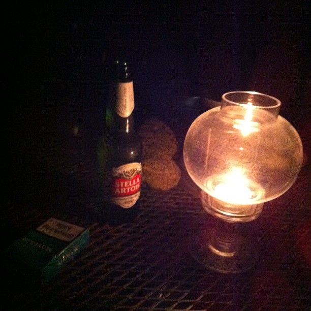 a lighted jar and bottle of beer sitting on a table