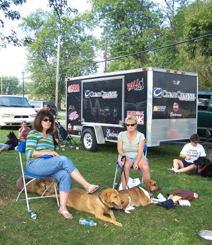 three people sitting in chairs next to two large dogs