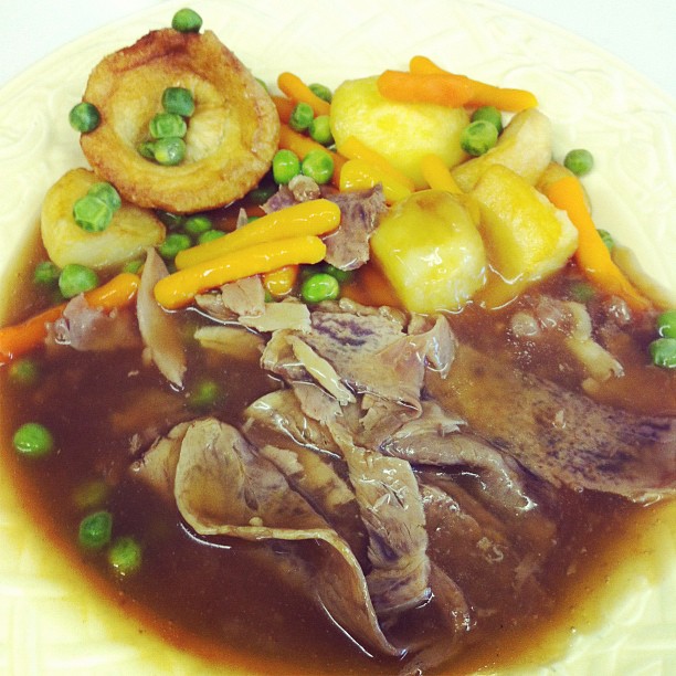 a plate topped with meat, potatoes and peas