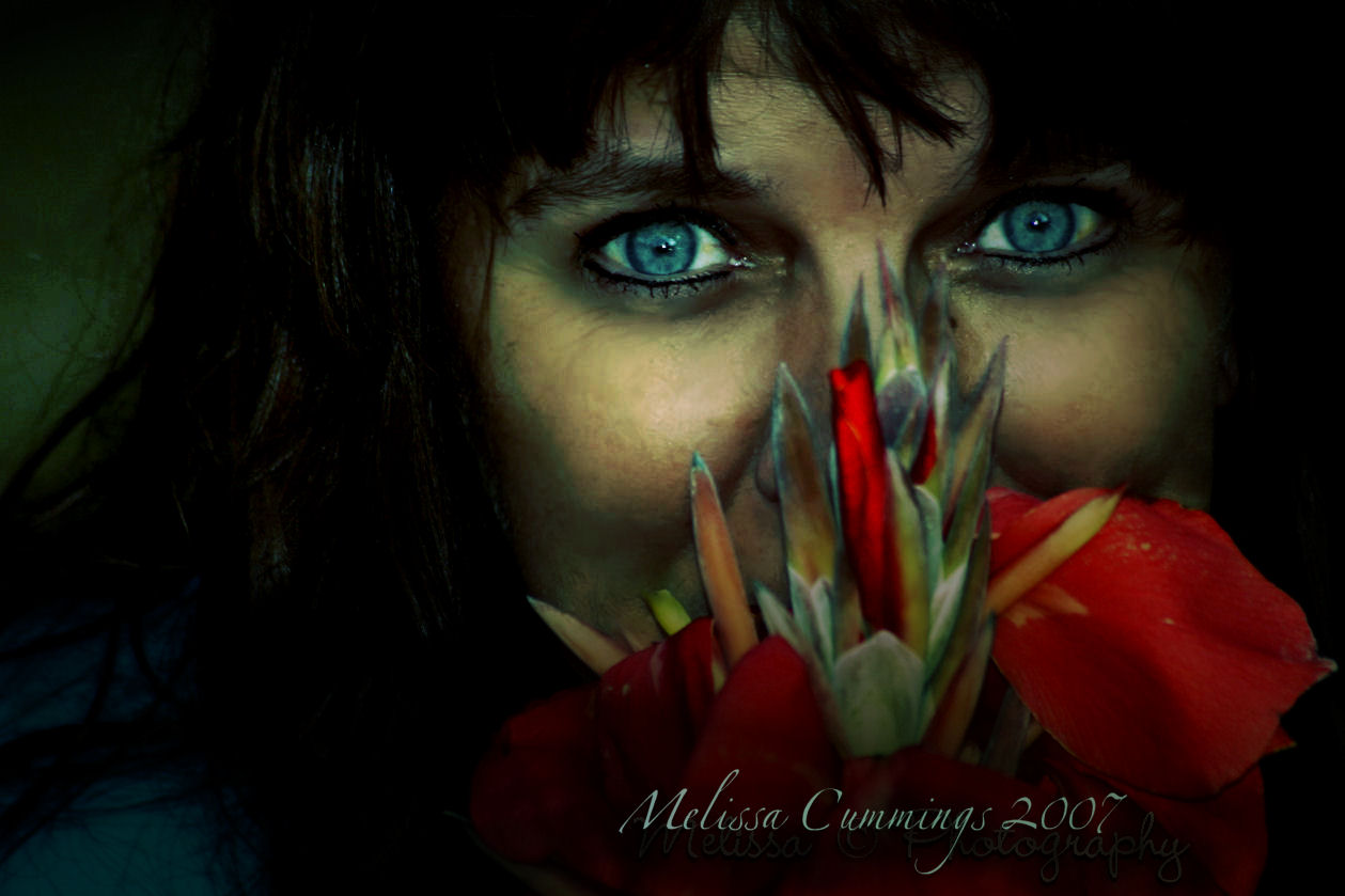 a person is staring through her eye, holding onto the red flower