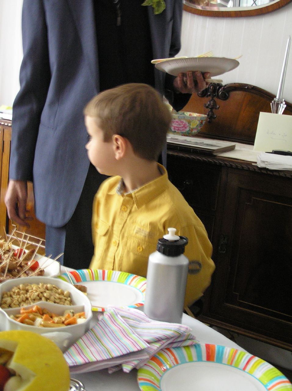 a little boy that is sitting at a table with food