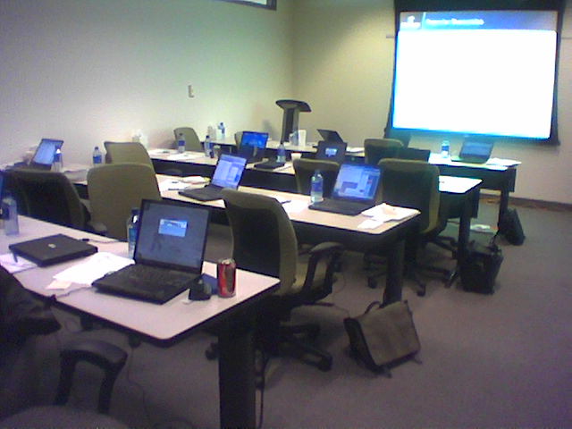 an empty classroom has laptops and laptop computers set up in rows