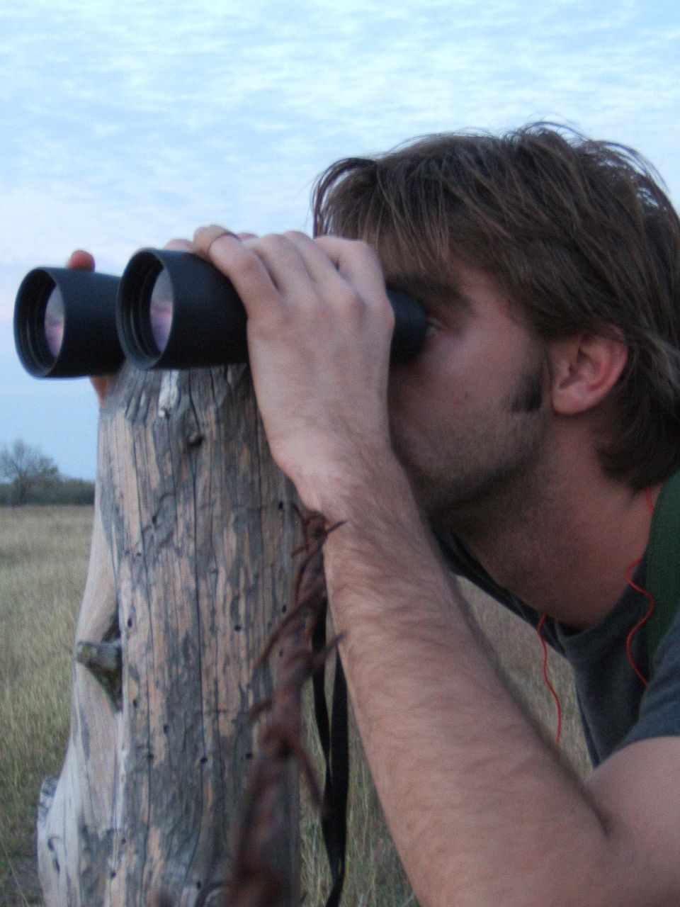 a man is leaning on a fence to look through a binoc