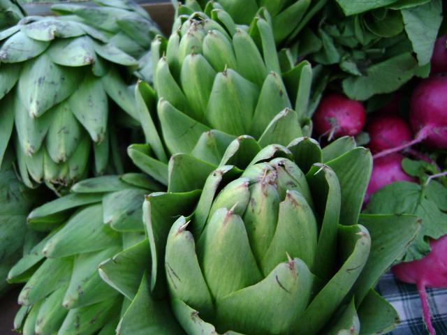 large green banana flower surrounded by other vegetables