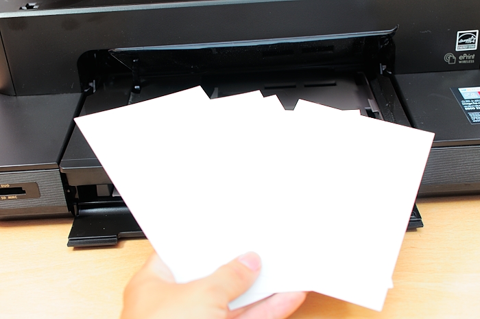 someone is placing several sheets of paper next to a printer