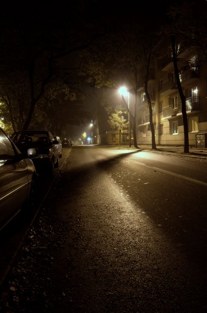two parked cars on a city street at night