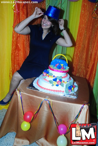 a woman sitting next to a three tiered cake
