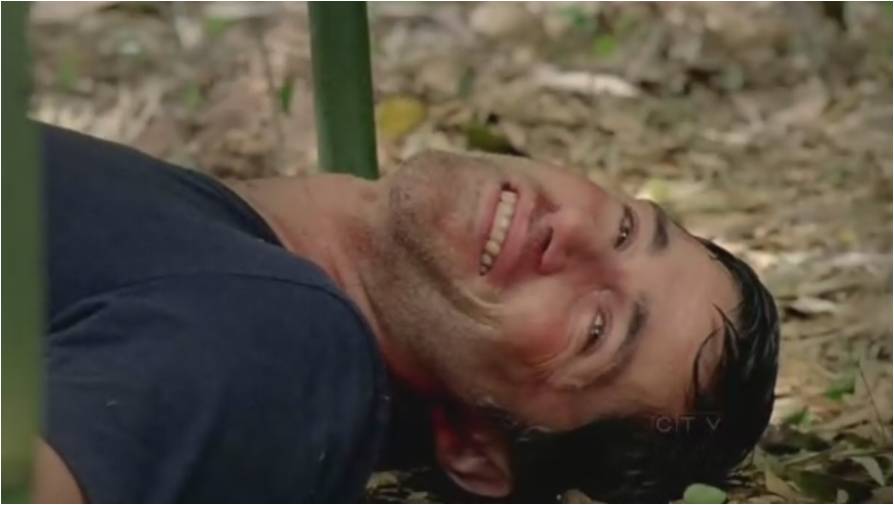 a close up of a man laying on the ground with his head under a tree