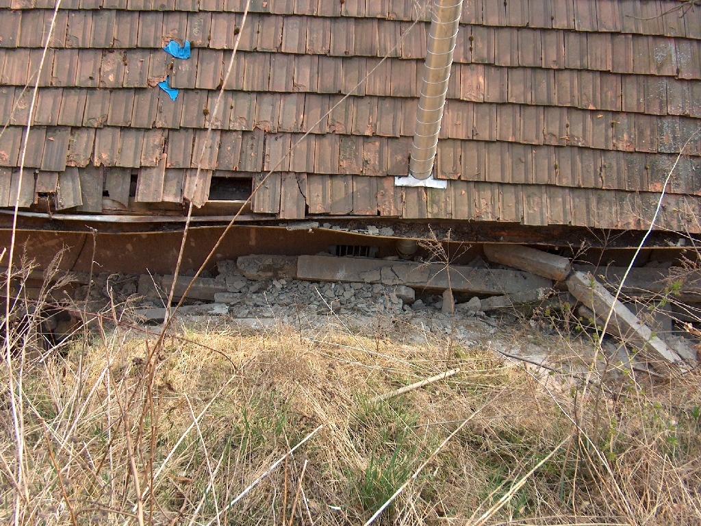 the gutter next to a brick house is falling apart