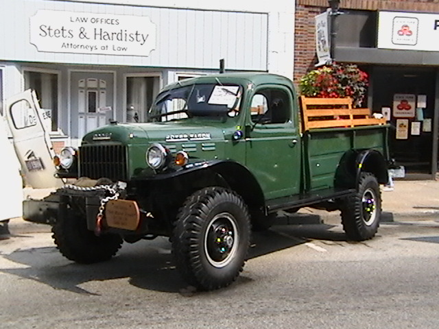 a large green and wooden truck is parked outside
