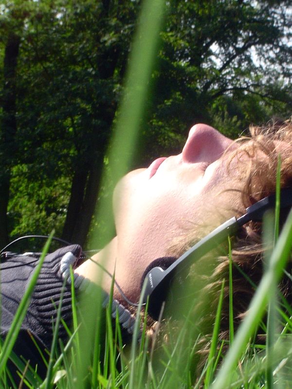 a man in a black hat with the face partially open laying in the grass