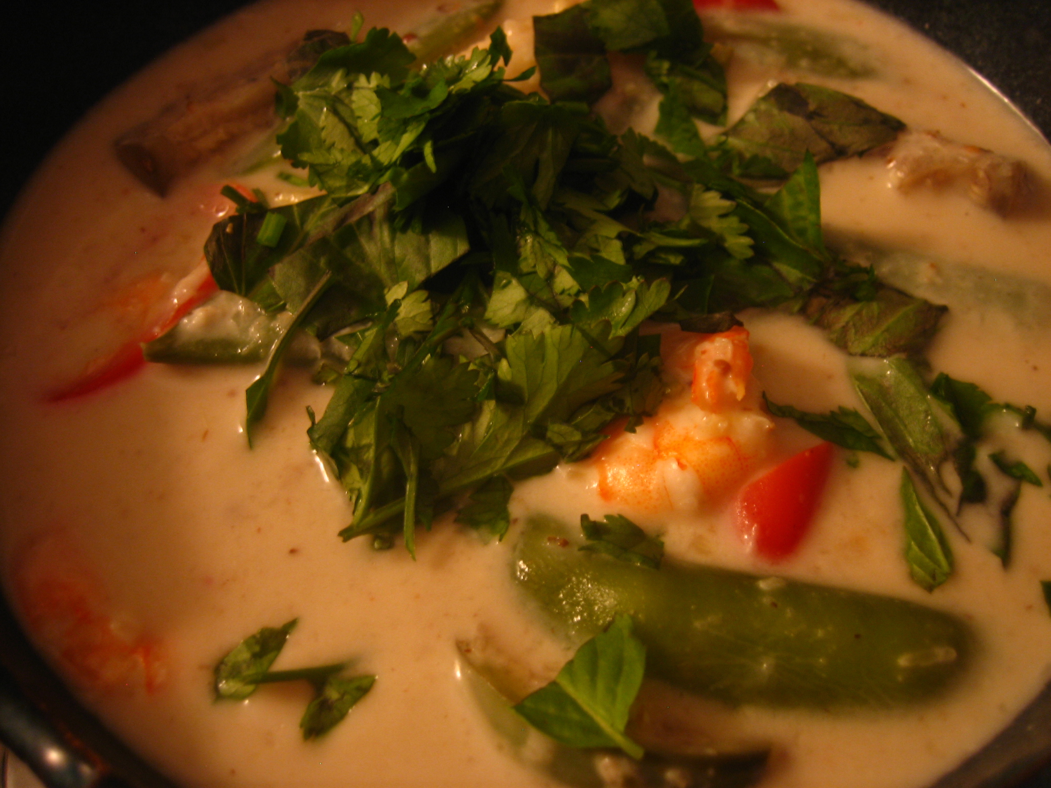 a white soup has green and red vegetables on top