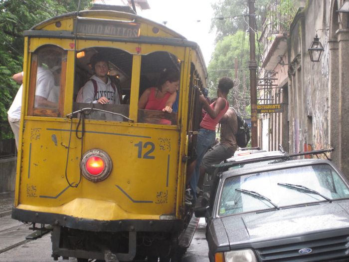 two people sitting in the bottom of a yellow streetcar on the street