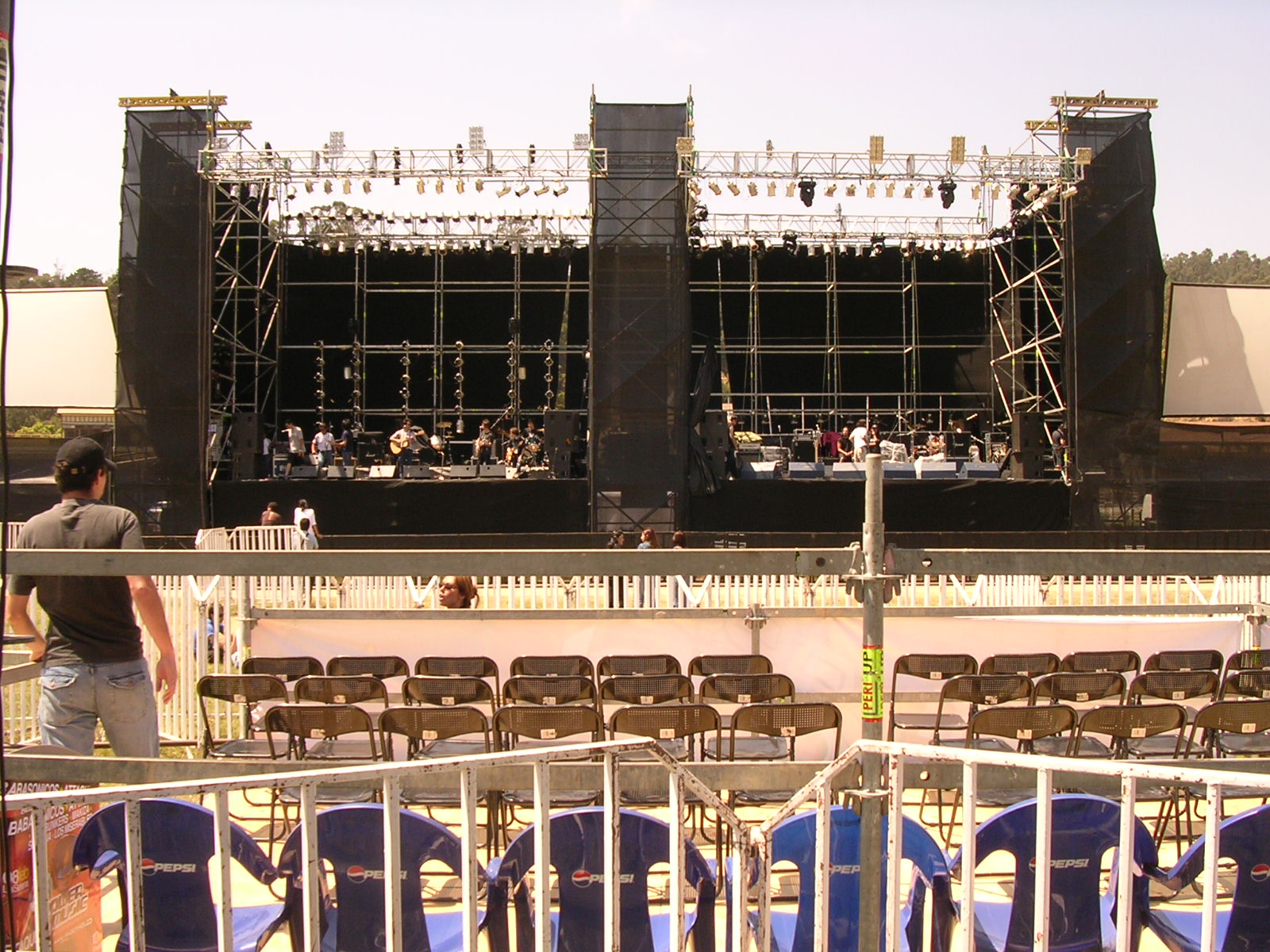 large stage set in back yard with several blue folding chairs