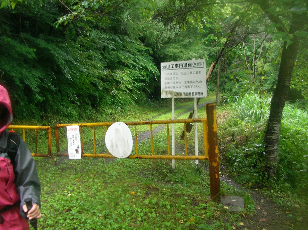 a boy in rain gear standing in front of a gate