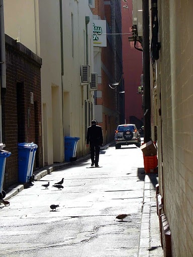 a man walking down an alley in a city