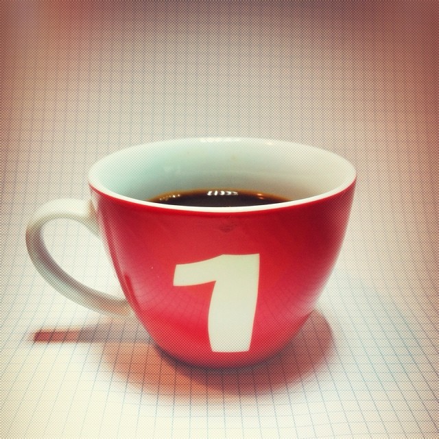a mug filled with coffee next to a red wall