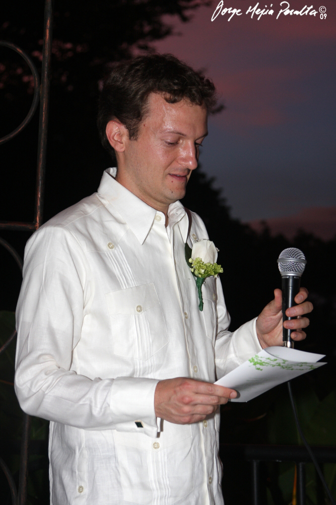 man in white suit holding flower and microphone