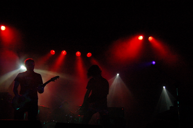 two guitar players and their guitars in the spotlight