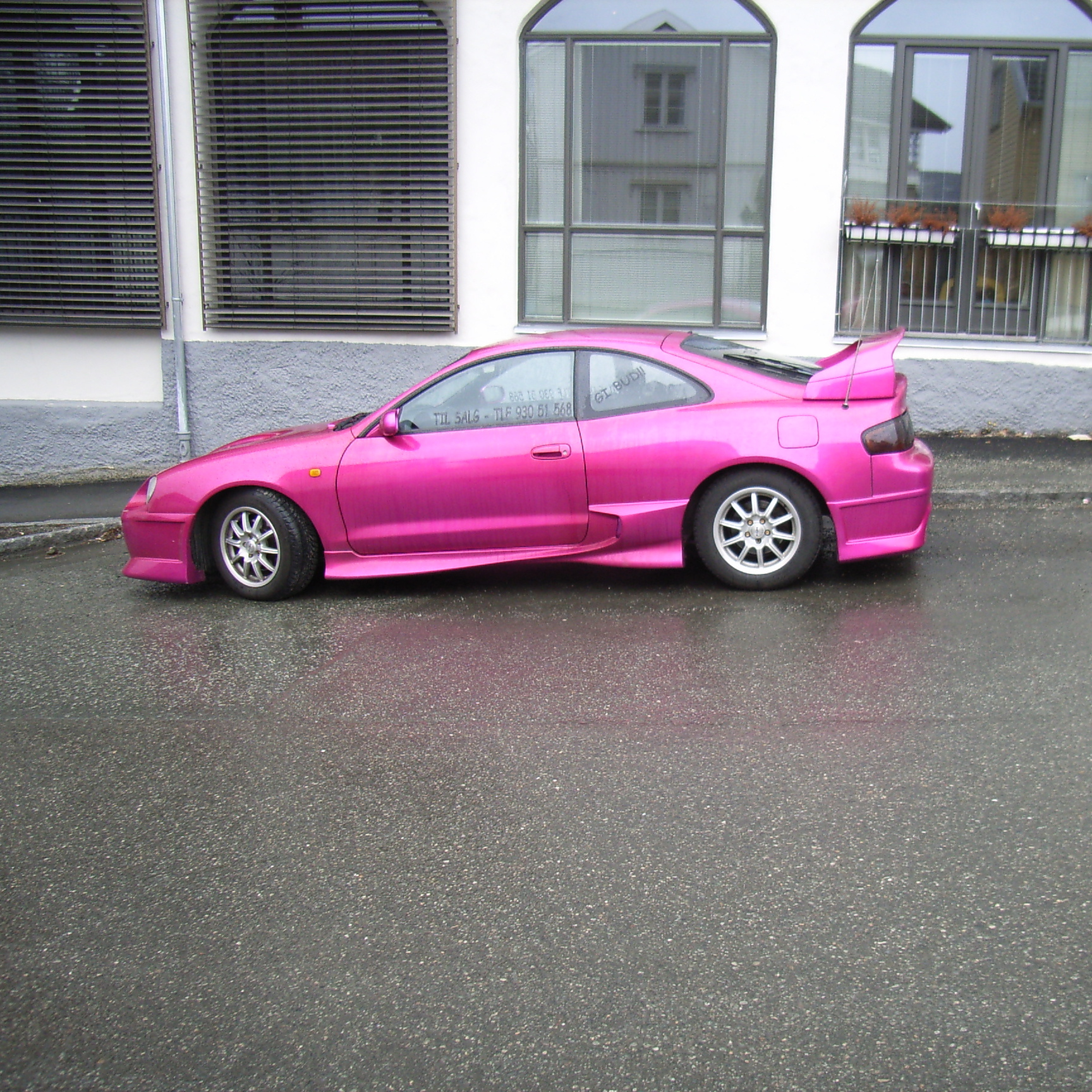 a car that is all pink and it's sitting in the road