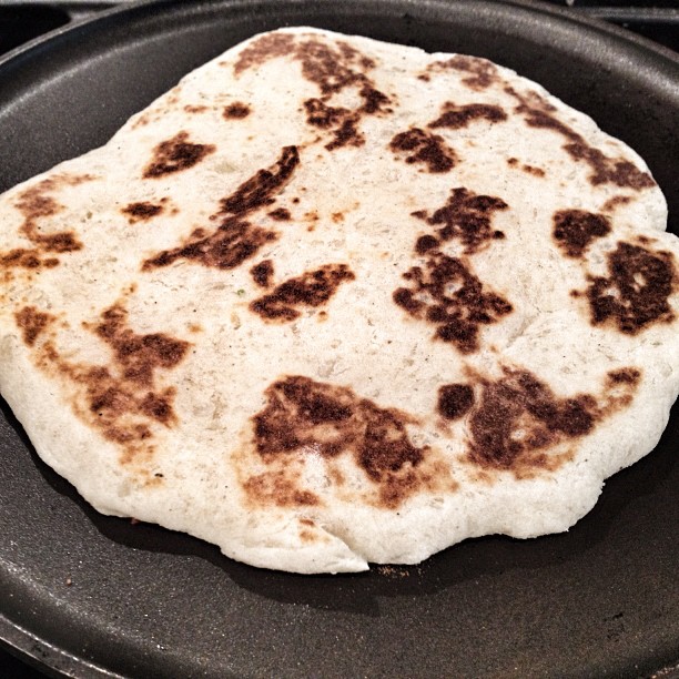 a tortilla cooking on a stove top in a black pan
