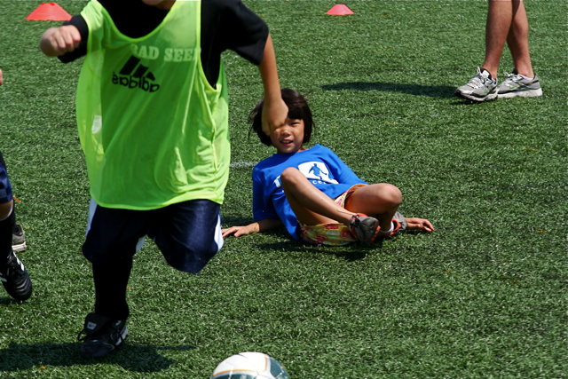 a boy running after a soccer ball on the grass