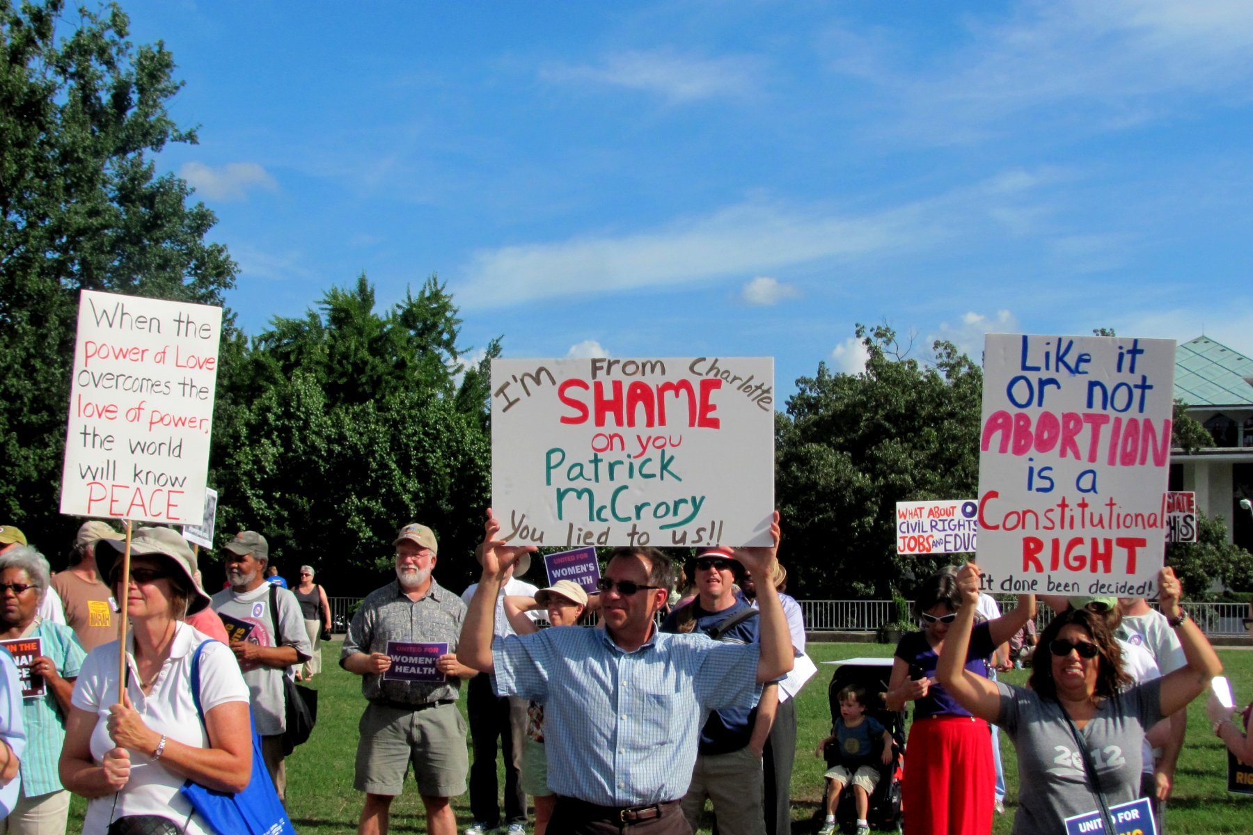 a group of people holding signs while standing in the grass