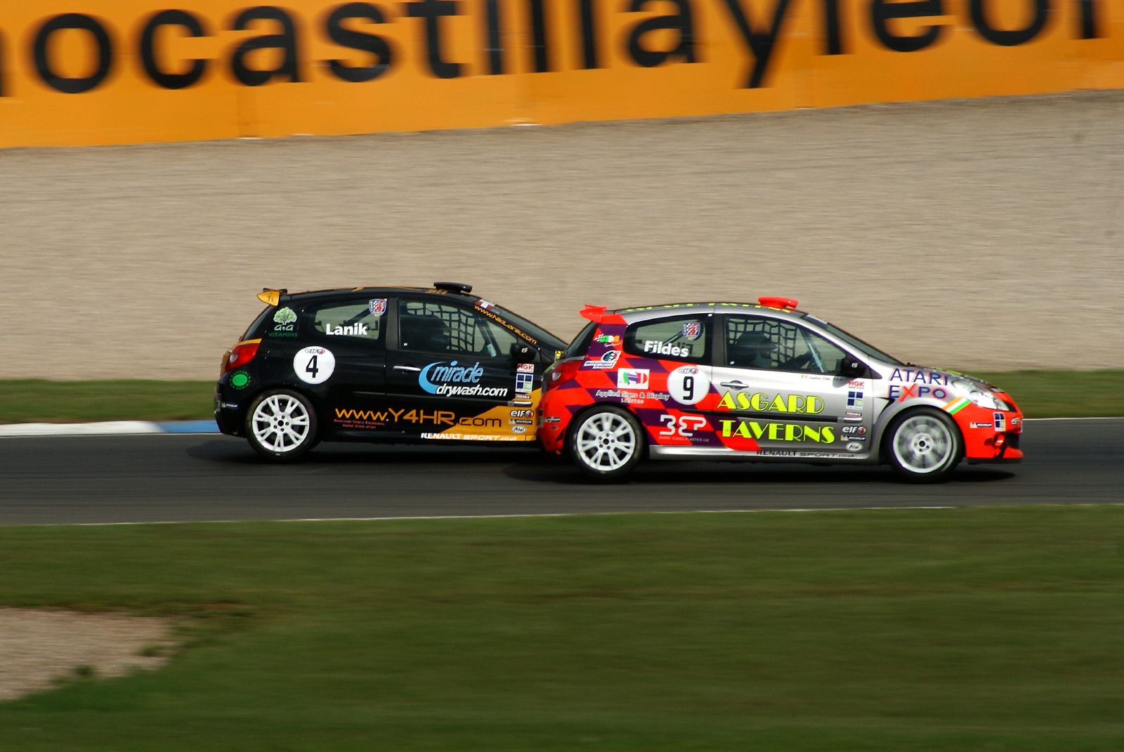 two small cars driving side by side on a race track