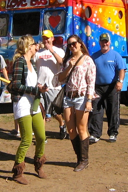 two women wearing boots standing in front of a colorful truck