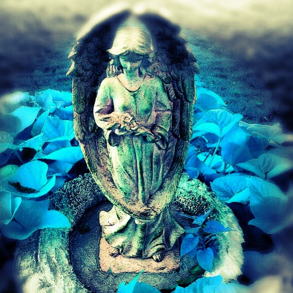 a statue sitting on top of a statue surrounded by blue flowers