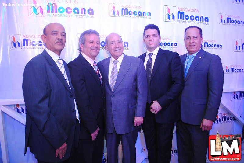 five men pose in front of a white wall