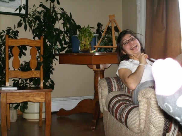 a smiling young woman sitting on a couch near plants and chairs