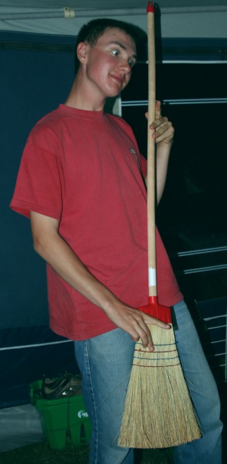 a young man holding a broom with one hand and making a face