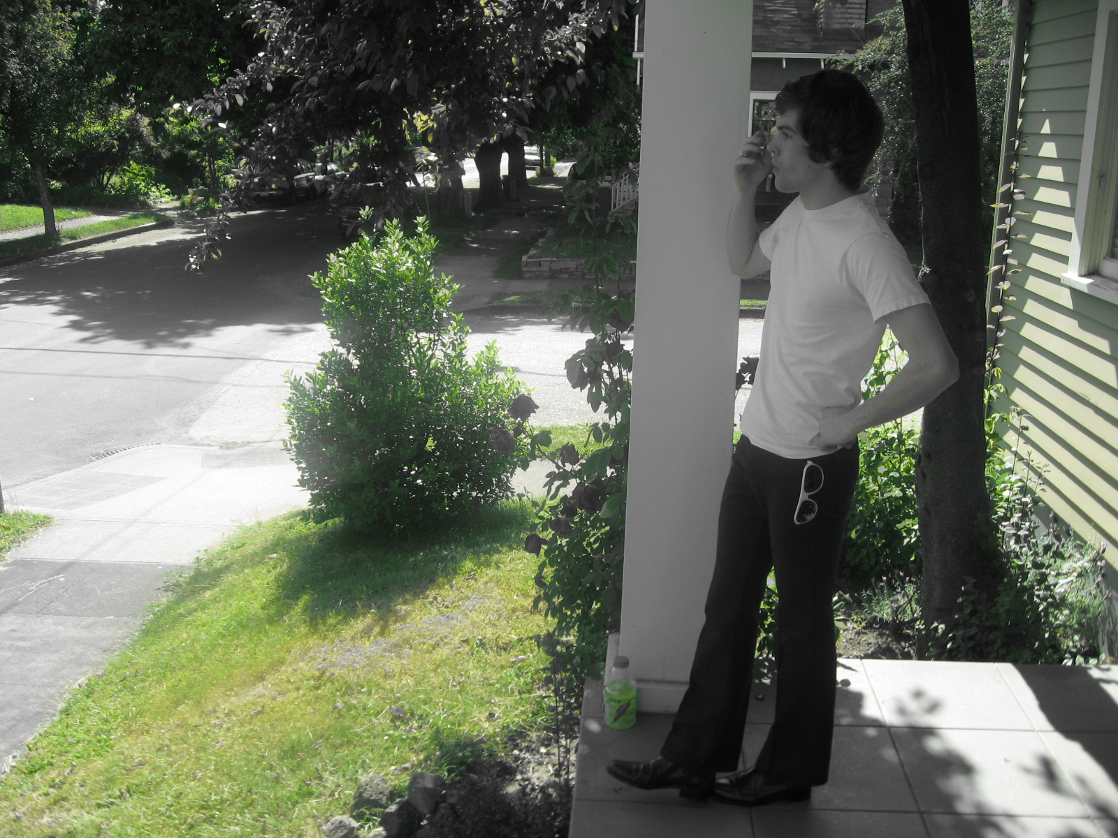 man in white shirt standing by the corner of a house