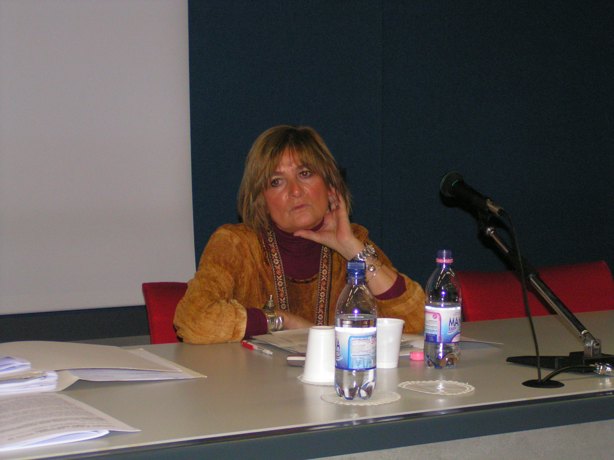 woman sitting at a table in front of a microphone in an event